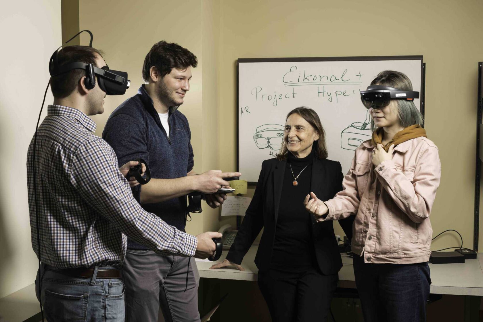 Jannick Rolland in a room with three graduate students wearing and using extended reality technology.